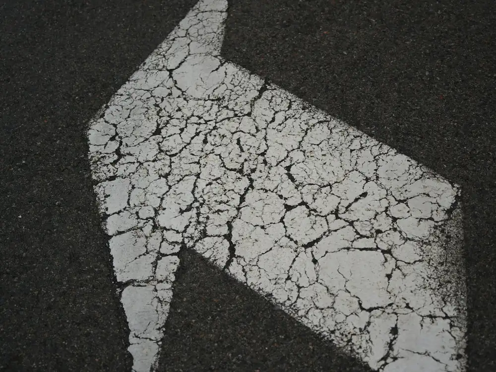 Faded, cracked arrow on old asphalt
